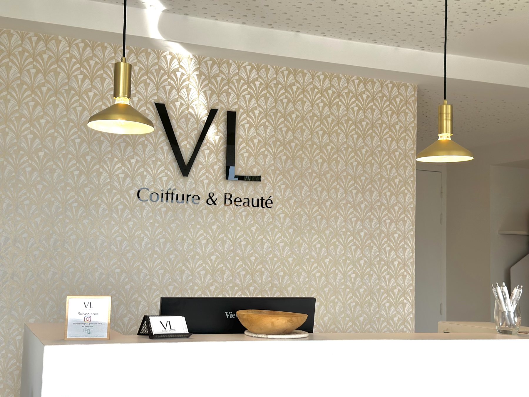 L'accueil du salon VL Coiffure & Beauté à Chalonnes-sur-Loire, logo VL et suspensions dorées